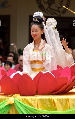 Chinesische Mädchen in Tracht, während eine Chinesische Neujahrsparade in eine Lotusblüte sitzen. Stockfoto