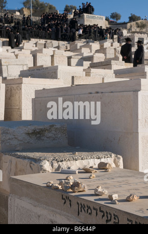 Israel Jerusalem Mount Of Olives Judenfriedhof Steine auf Gräber mit Gruppe orthodoxer Juden in Bkgd hautnah Stockfoto