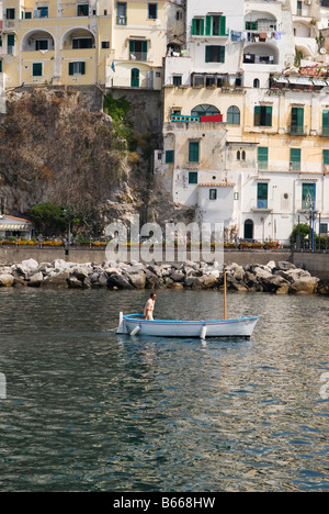 Eine lokale Fährmann steuert seine kleinen blauen und weißen Boot unter dem steilen Hang Gebäude von Amalfi, Kampanien, Italien Stockfoto