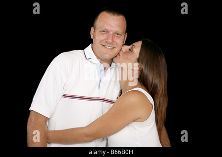 Junge schwangere Frau ihren Mann auf die Wange küssen schwarzen Hintergrund Stockfoto