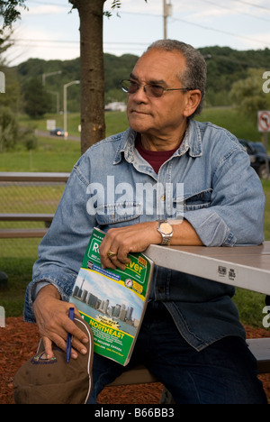 Ein senior Latino-Mann sitzt in einem park Stockfoto