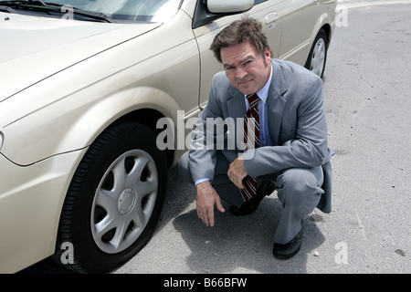 Ein Geschäftsmann mit einer Reifenpanne unterwegs sieht er verärgert Stockfoto