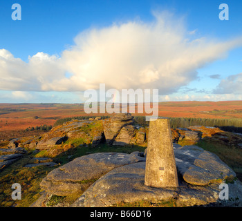 Licht des frühen Morgens und ein Regenbogen am Bellever Tor auf Dartmoor in South Devon UK mit der Triangulation Säule auf dem Gipfel Stockfoto