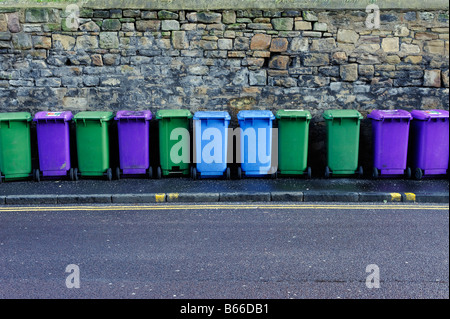 Linie der bunte recycling-Behälter aufgereiht vor einer Steinmauer Stockfoto