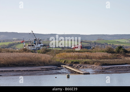 Ein Bagger macht seinen Weg entlang der Exeter gegenüberliegenden Topsham Kanal Fluss Exe im Vordergrund steht Stockfoto