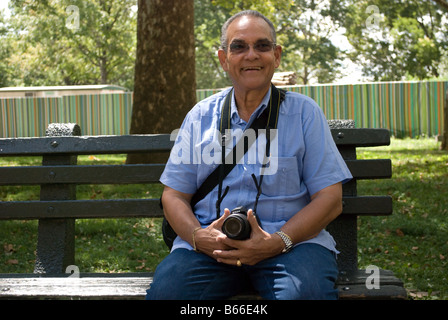 Ein senior Latino-Fotograf sitzt in einem park Stockfoto