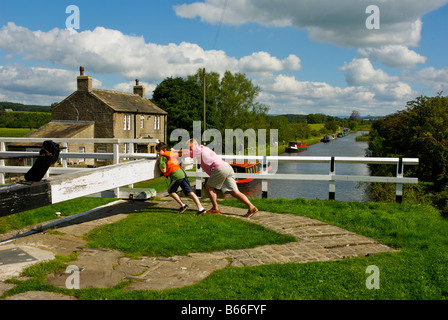 Mann und junge öffnen die Schleusen am Leeds-Liverpool-Kanal in der Nähe von Gargrave, North Yorkshire, England UK Stockfoto