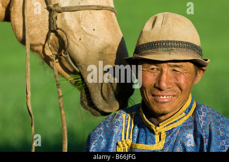 Grasland-Hirte in traditioneller Tracht mit Grass essen Pferd Xilinhot Innere Mongolei China Stockfoto