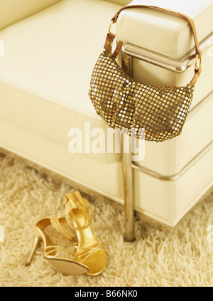 Golden High-Heeled Schuhe und Handtaschen von Sessel Stockfoto