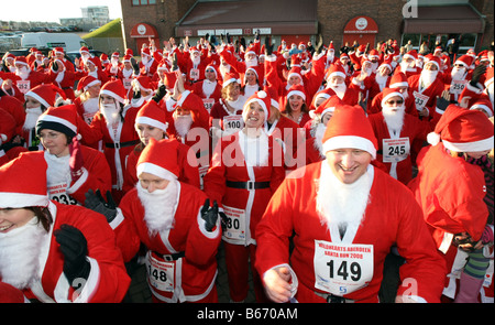 Line-up der Weihnachtsmänner tragen rote Weihnachtsmann-Kostüme, die Teilnahme an jährlichen Santa laufen entlang des Strandes in Aberdeen, Schottland, Vereinigtes Königreich Stockfoto