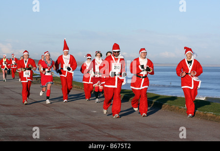 Line-up der Weihnachtsmänner tragen rote Weihnachtsmann-Kostüme, die Teilnahme an jährlichen Santa laufen entlang des Strandes in Aberdeen, Schottland, Vereinigtes Königreich Stockfoto