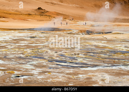 Touristen, schauen Sie in der Ferne in eine kochende Mudpot am Námafjall Geothermie Berggebiet, in der Nähe von Akureyri, Nordisland. Stockfoto