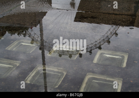 London Eye spiegelt sich in einer Pfütze des Regenwassers, spiegelt das typische London Wetter 2 Stockfoto