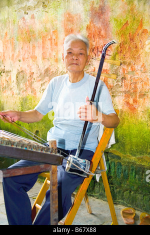 Senior Woman spielen Erhu, Fuli Dorf, Yangshuo, Provinz Guangxi, China Stockfoto