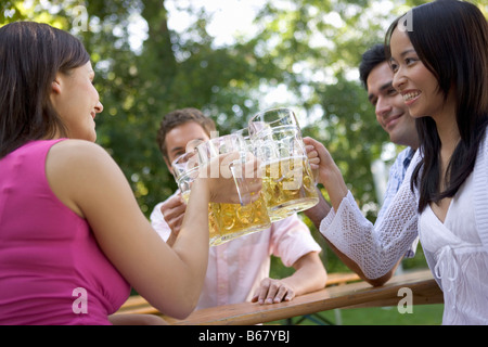 Vier Freunde in einem Biergarten klirrende Gläser, Starnberger See, Bayern, Deutschland Stockfoto