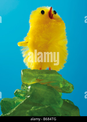 Gelbe Osterküken stehend auf einem Steinhaufen grünes Glas Stockfoto