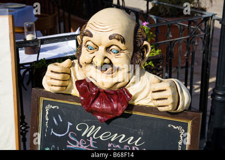 Schnitzen eines Mannes leckte sich die Lippen über eine Speisekarte an Bord vor einem Restaurant, St. Julians, Malta Stockfoto