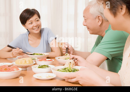 Mitte Erwachsene Frau, die mit ihren Eltern an einem Esstisch sitzen Stockfoto