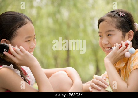 Zwei Mädchen auf ihren Handys sprechen und Lächeln Stockfoto