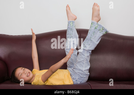 Seitenansicht eines Mädchens, das Spielen auf einer couch Stockfoto