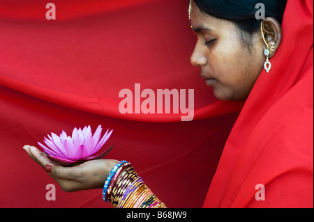Indische Frau bietet eine Nymphaea tropische Seerose Blume in einem roten sari Stockfoto
