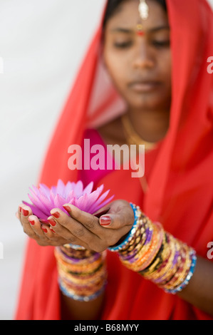 Indische Frau bietet eine Nymphaea tropische Seerose Blume in einem roten Sari. Andhra Pradesh, Indien Stockfoto