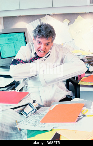 Geschäftsmann in Zwangsjacke am Schreibtisch Stockfoto