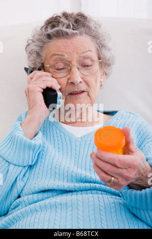 Ältere Frau Pille Flasche halten und telefonieren Stockfoto