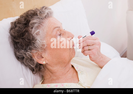 Ältere Frau mit Thermometer im Mund Stockfoto