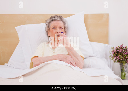 Ältere Frau mit Thermometer im Mund, Porträt Stockfoto