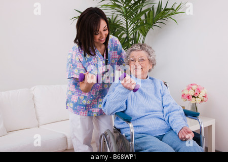Krankenschwester mit Hanteln mit senior Frau im Rollstuhl Stockfoto