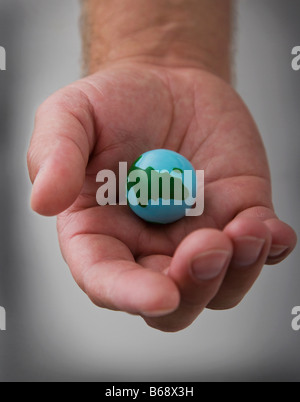 Des Mannes Hand, die kleine Weltkugel, close-up Stockfoto