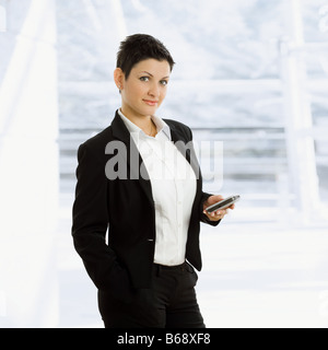 Glückliche junge Geschäftsfrau hält Handy-Lächeln Stockfoto