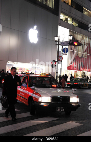 Ein roter japanischer Taxi fährt vorbei an den Apple Store in Ginza Japan Sayegusa Honkan 3 5 12 Ginza Chuo-Ku Tokyo Stockfoto