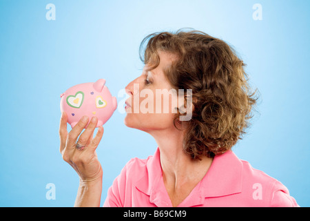 Frau küssen ein Sparschwein Stockfoto