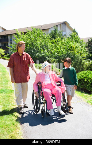 Mann mit einem Mädchen eine Frau in einem Rollstuhl zu unterstützen Stockfoto