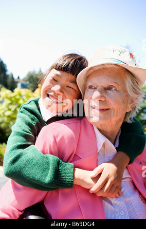 Mädchen umarmt ihre Großmutter in einem Garten Stockfoto