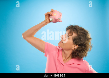 Frau, die versucht, Geld aus einem Sparschwein Stockfoto