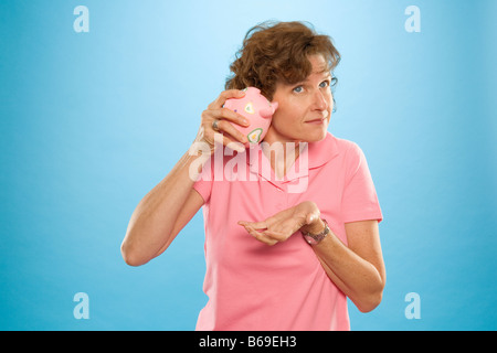 Frau, die versucht, Geld aus einem Sparschwein Stockfoto