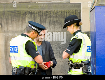 Zwei Polizisten sprechen mit einem Mann auf Edinburgh High Street, während die jährliche Edinburgh Fringe Festival Stockfoto