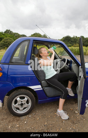 Junge Frau Elektroauto zu trinken Stockfoto