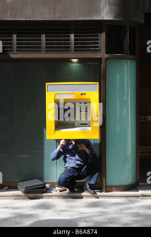 Ein Mann Reparaturen/Dienstleistungen einen Geldautomaten auf der Insel Mallorca Stockfoto
