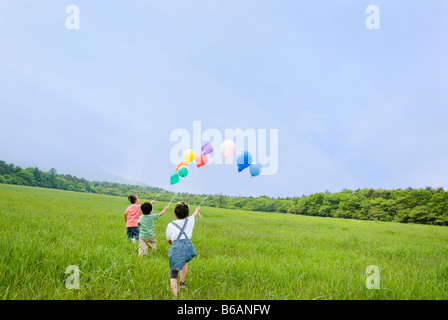 Kinder laufen mit Luftballons Stockfoto