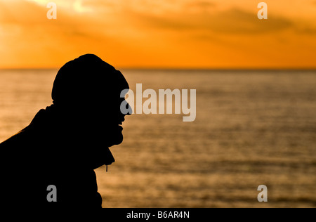 Die Silhouette eines Mannes, der Blick auf den Sonnenuntergang über Birling Gap in East Sussex. Stockfoto