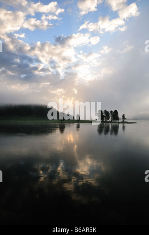 Sonnenaufgang an einem bewölkten blauen Himmel spiegelt sich in einem großen ruhigen Fluss im Yellowstone National Park Stockfoto