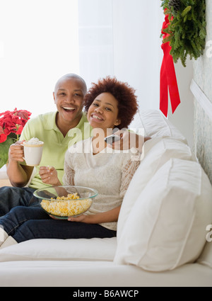 African Paar vor dem Fernseher mit Popcorn und heiße Schokolade Stockfoto