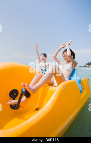 Zwei junge Frauen reiten auf Pedal Boot Stockfoto