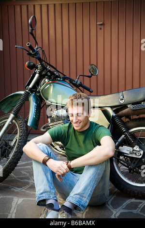 Porträt des jungen Mannes stützte sich auf Motorrad Stockfoto
