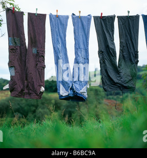 Alte, gepatchte Denim-Jeans und -Hosen trocknen kopfüber im Freien Auf einer Wäscheleine mit Kleidung Stifte Haken Wales UK KATHY DEWITT Stockfoto
