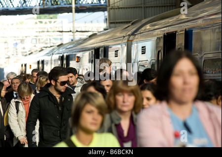 Passagiere, die aus einem Zug auf einen überfüllten Bahnhofssteig in Großbritannien steigen. Stockfoto